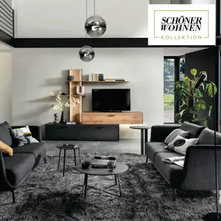 Wohnzimmer mit dunklen Sofas, Couchtischen, TV-Möbel und Logo SCHÖNER WOHNEN KOLLEKTION